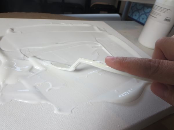 apply gel medium on top of the canvas using a spatula