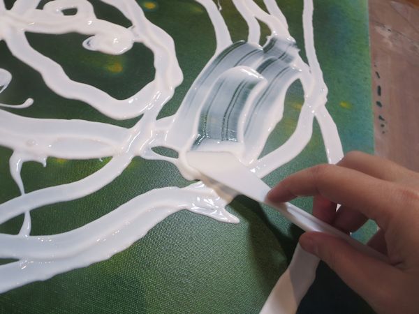 spreading gel medium onto the canvas