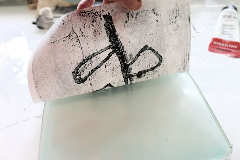 Print your monoprint by applying paper on the plate and carefully pressing so the paper is fully in contact with the plate. This time you want to leave the paper for at least 15 minutes so it has time to soak all the paint n the plate.